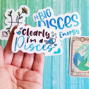 May include: A set of five stickers featuring the astrological sign Pisces. The stickers are white with blue and black lettering and illustrations. One sticker says "Clearly I'm a Pisces" with a blue fish illustration. Another sticker says "Big Pisces Energy".