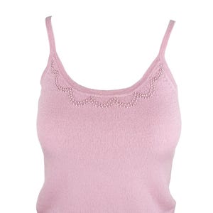 Op de afbeelding: Een lichtroze camisole top met dunne bandjes. De halslijn is versierd met een geschulpte rand van kleine, witte kralen. De top is gemaakt van een zachte, geribbelde gebreide stof en biedt een eenvoudige maar elegante stijl.