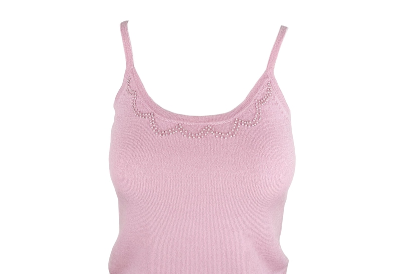 Op de afbeelding: Een lichtroze camisole top met dunne bandjes. De halslijn is versierd met een geschulpte rand van kleine, witte kralen. De top is gemaakt van een zachte, geribbelde gebreide stof en biedt een eenvoudige maar elegante stijl.