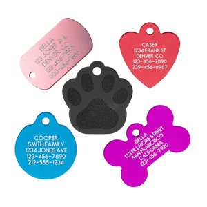 May include: A collection of colorful pet ID tags in various shapes: a pink rectangle, a red heart, a blue circle, a purple bone, and a black paw print. Each tag has a hole for attachment and includes engraved text with pet and owner information.