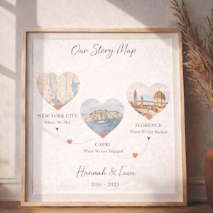 Könnte beinhalten: Ein gerahmter Druck mit dem Titel "Our Story Map" mit Aquarellillustrationen von New York City, Capri und Florenz, verbunden durch gestrichelte Linien und Herzen. Die Namen "Hannah & Luca" und die Jahre "2016-2023" sind ebenfalls abgebildet.