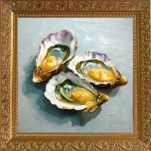 May include: An oil painting of three opened oysters with yellow and green interiors, set against a light blue background. The artwork is framed in a gold, ornate frame, adding a touch of elegance to the still life.
