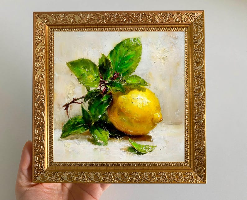 May include: A framed oil painting of a lemon with green leaves. The lemon is a vibrant yellow, and the leaves are a lush green. The painting is in a gold ornate frame, adding a touch of elegance to the artwork.