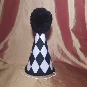 May include: A black and white checkered party hat with a black pom-pom on top.