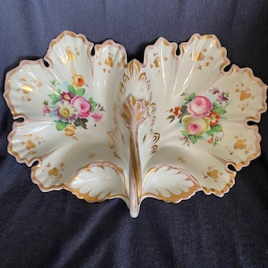 May include: A white porcelain serving dish with a floral design. The dish is divided into two sections and has a scalloped edge with a pink border and gold trim. Floral bouquets in pink, yellow, and purple adorn each section.