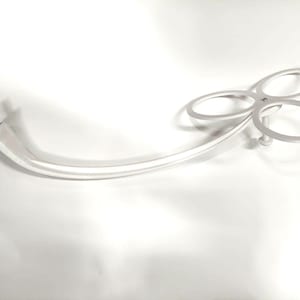 Könnte beinhalten: Weißer Küchenutensilienhalter aus Kunststoff mit einem gebogenen Arm und drei runden Becherhaltern.