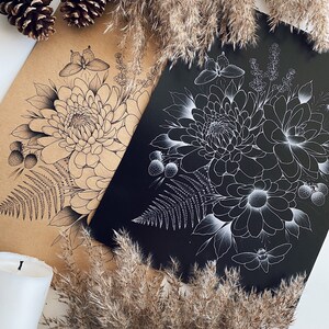 May include: Two floral art prints, one on kraft paper and the other on black, featuring detailed line drawings of dahlias, ferns, and butterflies. The kraft paper print has a sepia tone, while the other is white on black. Decorative elements include pine cones and dried grasses.