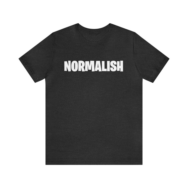 以下が含まれることがあります： 前面に白い文字で「NORMALISH」がプリントされたダークヘザーグレーのTシャツです。
