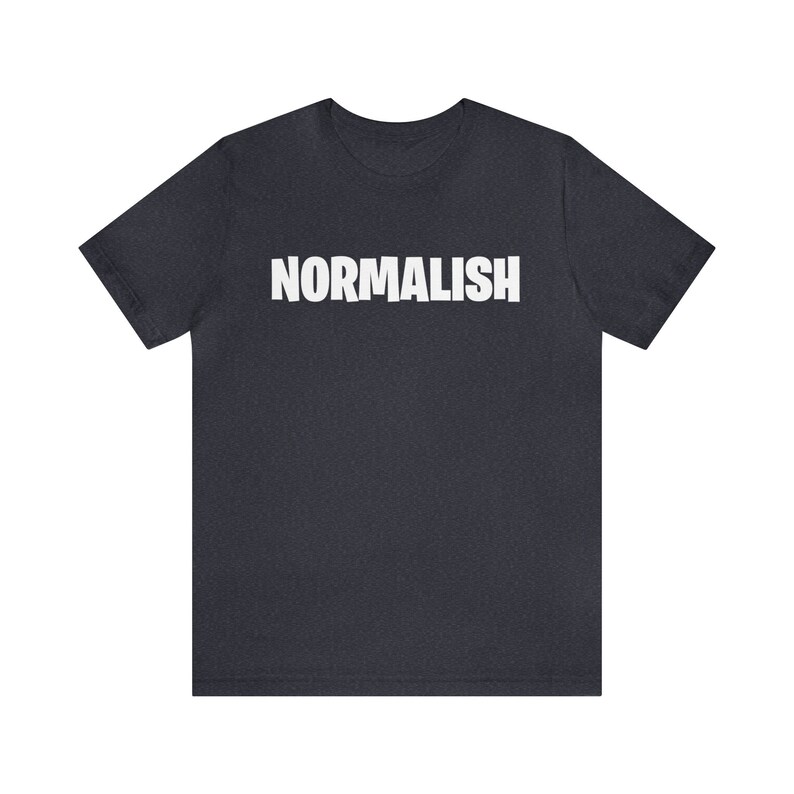 以下が含まれることがあります： 前面に白い文字で「NORMALISH」とプリントされた濃い青色のTシャツです。