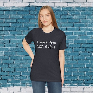 May include: A dark heather grey t-shirt with the text "i work from 127.0.0.1" printed in white.