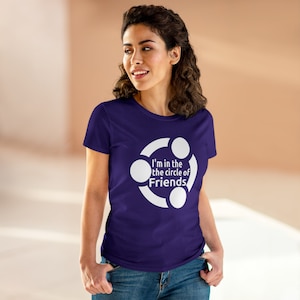 Puede incluir: Camiseta morada con un gráfico blanco de tres personas tomadas de la mano en un círculo. El texto "I'm in the circle of Friends" está escrito debajo del gráfico.