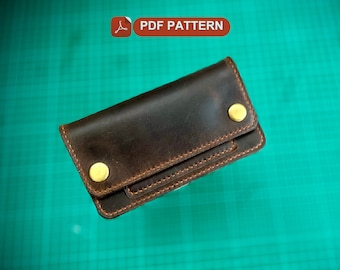 May include: A brown leather wallet with two gold snaps and a folded design. The wallet is on a green surface.