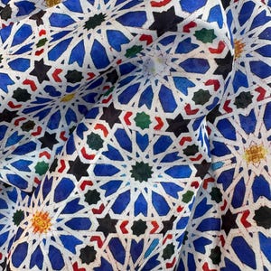 Moroccan tile-inspired silk scarf with blue, white, and orange geometric motifs; large women's neck scarf worn as a wrap.