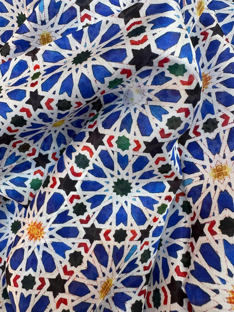 Moroccan tile-inspired silk scarf with blue, white, and orange geometric motifs; large women's neck scarf worn as a wrap.
