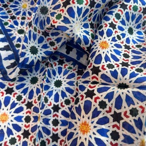 Moroccan tile-inspired silk scarf with blue, white, and orange geometric motifs; large women's neck scarf worn as a wrap.