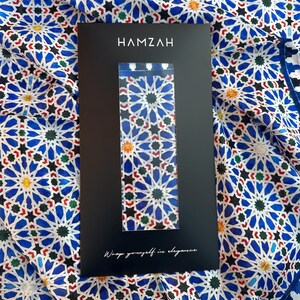Moroccan tile-inspired silk scarf with blue, white, and orange geometric motifs; large women's neck scarf worn as a wrap.
