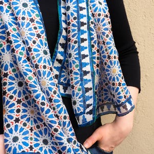Moroccan tile-inspired silk scarf with blue, white, and orange geometric motifs; large women's neck scarf worn as a wrap.