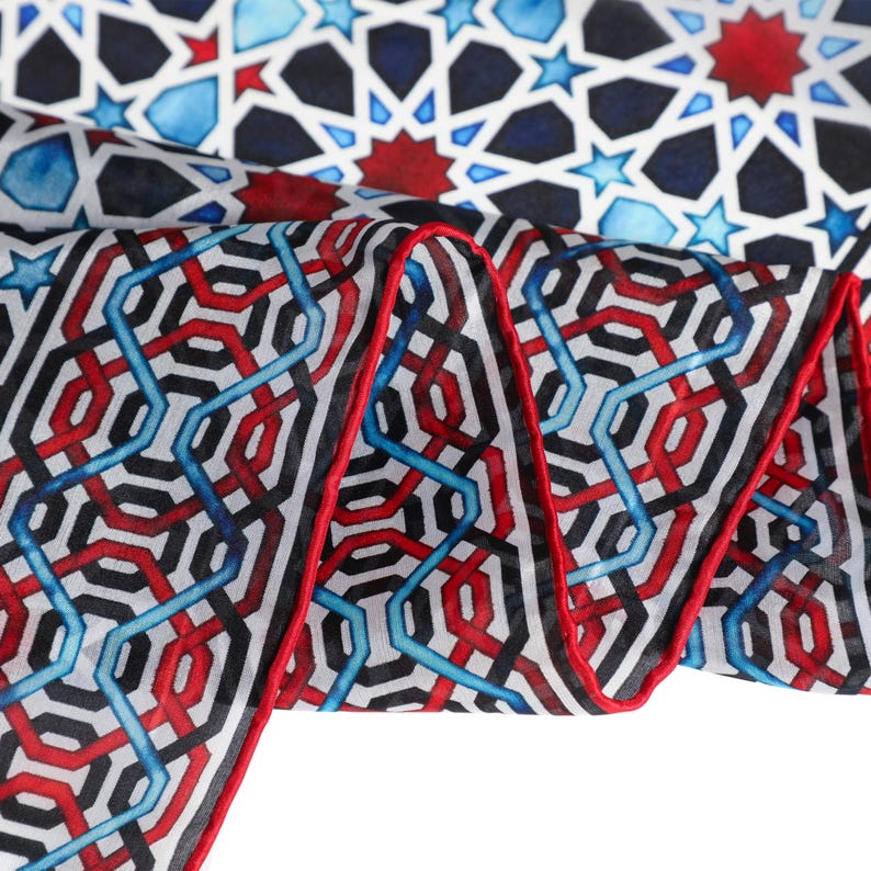 Large mulberry-silk scarf with Islamic geometry and Alhambra-inspired pattern, red border draped over a woman's shoulders.