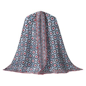 Large mulberry-silk scarf with Islamic geometry and Alhambra-inspired pattern, red border draped over a woman's shoulders.