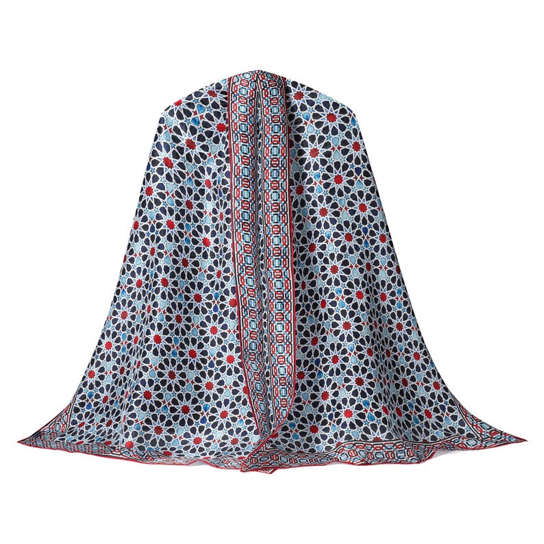 Large mulberry-silk scarf with Islamic geometry and Alhambra-inspired pattern, red border draped over a woman's shoulders.