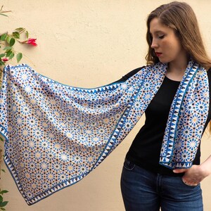 Moroccan tile-inspired silk scarf with blue, white, and orange geometric motifs; large women's neck scarf worn as a wrap.