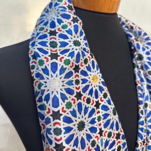 Moroccan tile-inspired silk scarf with blue, white, and orange geometric motifs; large women's neck scarf worn as a wrap.
