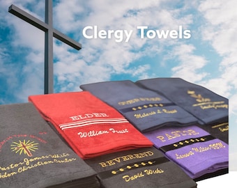 May include: A set of five clergy towels with embroidered titles, including "Elder", "Reverend", "Pastor", and "Other Stuff". The towels are in various colors, including red, gray, blue, and purple. The towels are stacked on top of each other, with the top towel being the "Elder" towel.