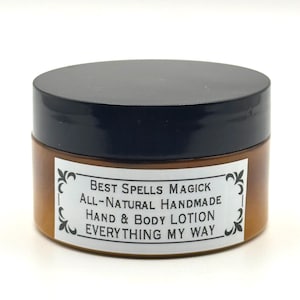 May include: A jar of hand and body lotion with a black lid and a brown body. The label reads "Best Spells Magick All-Natural Handmade Hand & Body Lotion EVERYTHING MY WAY."