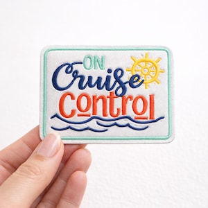 May include: Embroidered patch with the words "ON Cruise Control" in blue, orange, and green. A yellow ship's wheel and blue waves are also featured on the white background. The patch has a light green border.
