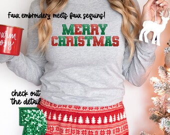 May include: A gray long-sleeved shirt with the text "Merry Christmas" in red and green glitter. The shirt is paired with red and white patterned pajama pants. The text "Faux embroidery meets faux sequins!" is written above the Christmas greeting.