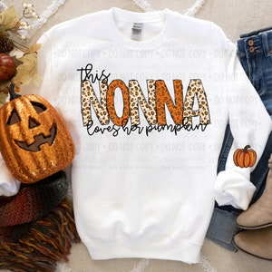 May include: White sweatshirt with the text "This Nonna loves her pumpkins" in orange and black letters with a leopard print pattern.