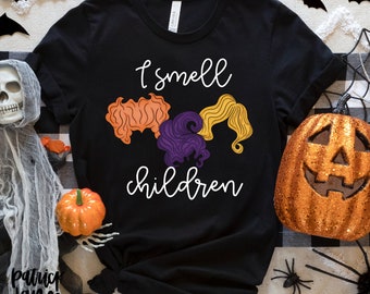 May include: Black t-shirt with a white graphic of three witches' hair with the text "I smell children".