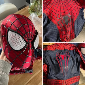 Op de afbeelding: Een rood en zwart Spider-Man kostuum, inclusief masker en pak. Het masker heeft witte mesh oogbedekkingen en een zwart webdesign. Het pak heeft een spinnenembleem op de borst en rug. Het kostuum is gemaakt van een textuurstof.