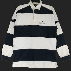 May include: A long-sleeved rugby shirt with alternating black and white horizontal stripes. The shirt features a collared neckline, a three-button placket, and the Guinness logo embroidered on the chest.