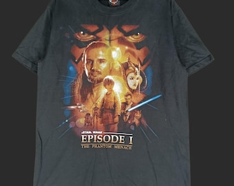 May include: Dark gray Star Wars Episode I t-shirt featuring a movie poster design. The graphic includes characters like Qui-Gon Jinn, Anakin Skywalker, and Queen Amidala, with the film's title prominently displayed.