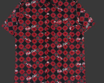 May include: Black button-down short-sleeve shirt with a red floral pattern and the text "Pelle Pelle" in white. The shirt has a collared neckline and a chest pocket. The shirt is made of a lightweight fabric.