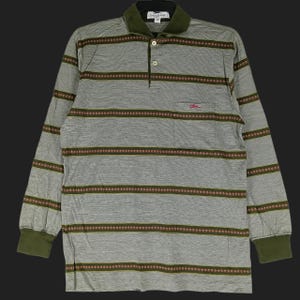 May include: Gray long-sleeved polo shirt with horizontal brown and red striped pattern. Features a green collar and cuffs, a chest pocket with a small logo, and a three-button placket. The shirt has the Longchamp logo on the collar.