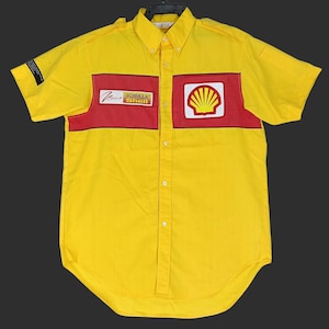 Puede incluir: Camisa amarilla de manga corta con detalles rojos y el logo de Shell. La camisa tiene cuello abotonado y corte entallado. Presenta el logo de Shell y texto. Fabricada en tejido ligero, adecuada para uso casual.