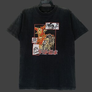 May include: Black t-shirt featuring a colorful graphic design with Japanese text and comic-style illustrations. The design includes a central image of a robot and several smaller panels with character portraits. The shirt has a vintage, faded look.