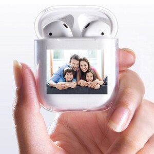 K&ouml;nnte beinhalten: Transparente AirPods-H&uuml;lle mit Familienfoto. Die transparente H&uuml;lle zeigt ein Bild einer l&auml;chelnden vierk&ouml;pfigen Familie. Wei&szlig;e AirPods sind im ge&ouml;ffneten Geh&auml;use sichtbar und verbinden Funktionalit&auml;t mit Personalisierung.