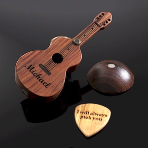Puede incluir: Un estuche de madera con forma de guitarra con el nombre Michael grabado en el frente, acompañado de una tapa de madera a juego en forma de cúpula y una púa de madera clara con el texto grabado I will always pick you.