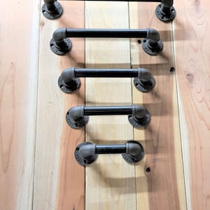 May include: Five black metal pipe industrial style handles of different lengths mounted on a wooden surface.