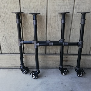 May include: Three black metal table legs with adjustable height and wheels. Each leg has a black metal plate on top and a black metal wheel on the bottom.