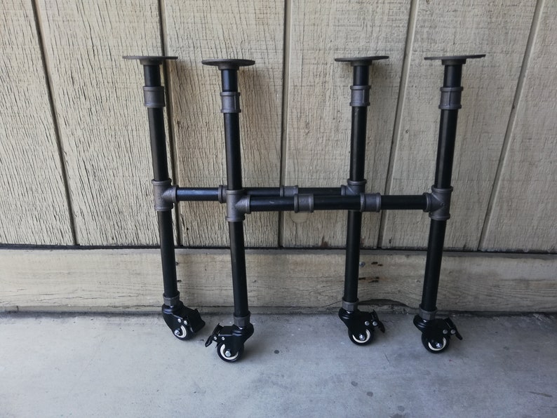 May include: Three black metal table legs with adjustable height and wheels. Each leg has a black metal plate on top and a black metal wheel on the bottom.