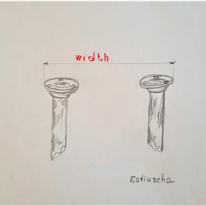 May include: A hand-drawn illustration of two gray columns with a flat top. The word "width" is written in red above the columns. The word "Katiuschka" is written in black at the bottom of the image.