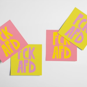 May include: Four sticky notes with the text "FCK AFD" written on them. Two notes are yellow with purple text and two notes are pink with yellow text.