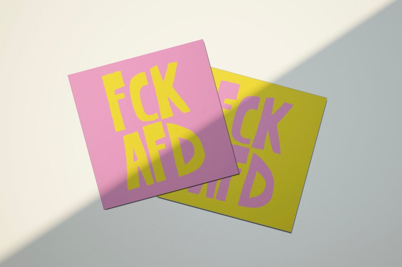 May include: Two square cards with the text "FCK AFD" printed in yellow letters on a pink and yellow background.