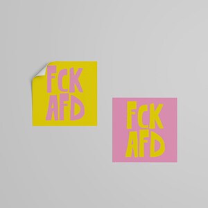 May include: Two square stickers with the text "FCK AFD" in pink letters on a yellow background and yellow letters on a pink background.