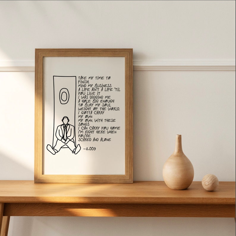 May include: Black and white illustration of a person sitting on a ledge with a circle behind them. The illustration is accompanied by a handwritten lyric from a song. The lyrics read: "Take my time to finish mind my business a life ain't a life 'til you live it I was digging me a hole big enough to bury my soul weight of the world. I gotta carry my own my own with these songs I can carry you home I'm right here when you're scared and alone -2.009"