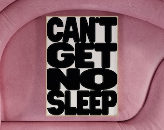 May include: A white framed poster with black text that reads "CAN'T GET NO SLEEP". The poster is hanging on a pink wall.